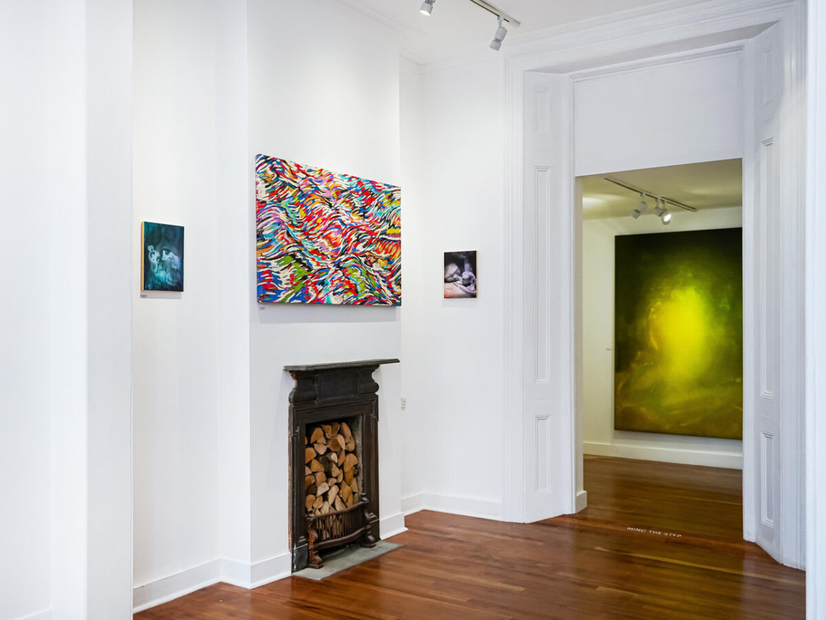 Vista detallada de la pared izquierda de Terraforming en Museum Street, 2025, con dos obras de pequeño formato de Nelson Hernández y una chimenea victoriana. Al fondo, gran pintura verde-amarilla en la sala contigua.