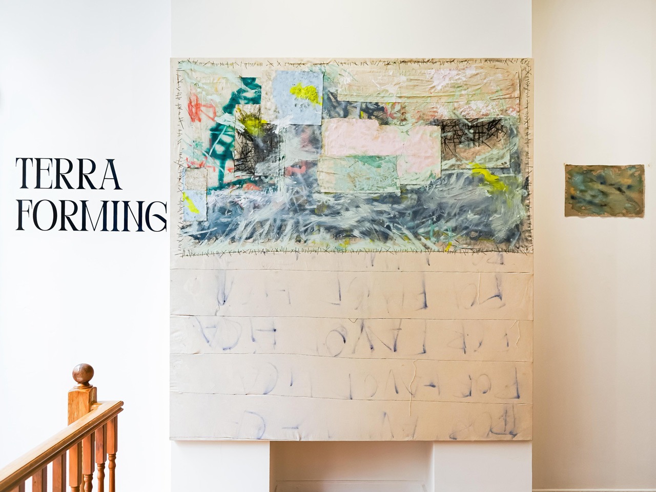 Entrance area of Terraforming at Museum Street, 2025, with TERRA FORMING lettered on the wall. Large mixed-media work on unprimed canvas with coloured patches, visible stitching, and faint writing in the lower half. A small landscape painting hangs to the right.