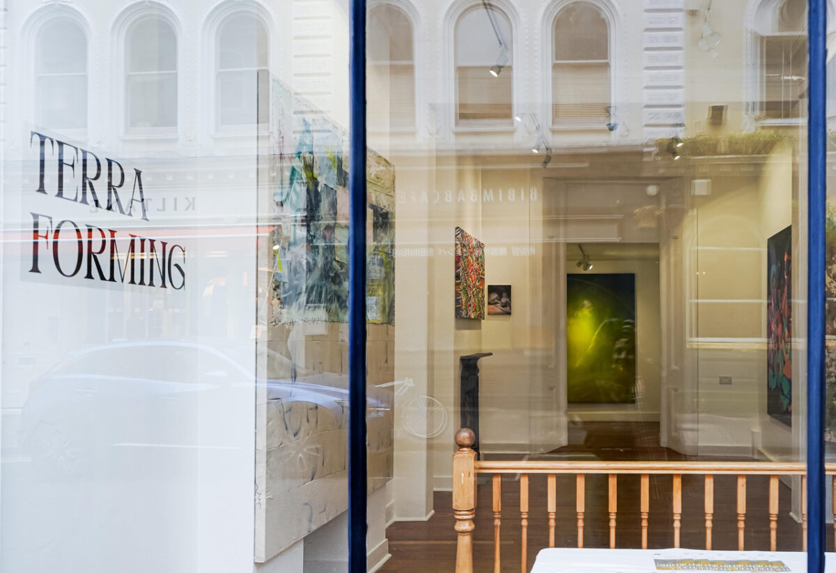 Vista desde el exterior de la galería en Museum Street, Bloomsbury, 2025. El texto TERRA FORMING en el vidrio se superpone con el reflejo de la arquitectura victoriana de enfrente; al interior se distinguen las obras de la exposición Terraforming.