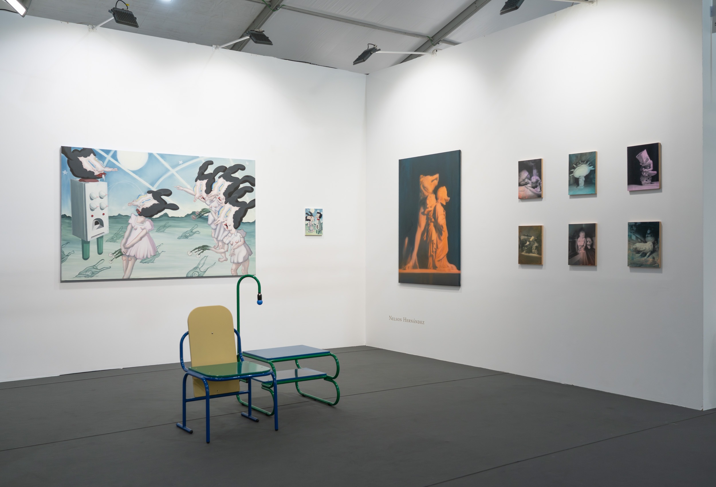 Isabel Croxatto Galería stand at CAN Art Fair Madrid 2026 seen from the aisle, with a colourful designer chair in the foreground and paintings by Carolina Muñoz and Nelson Hernández on the walls behind