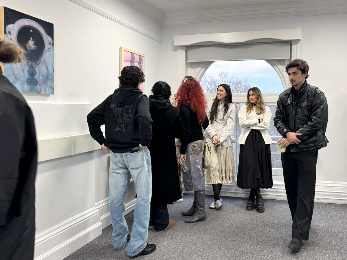 Visitantes durante el opening de Loop State en D Contemporary, Londres, 2026. Al fondo, Fever dream (astronaut) colgado junto a otra obra de la exposición colectiva