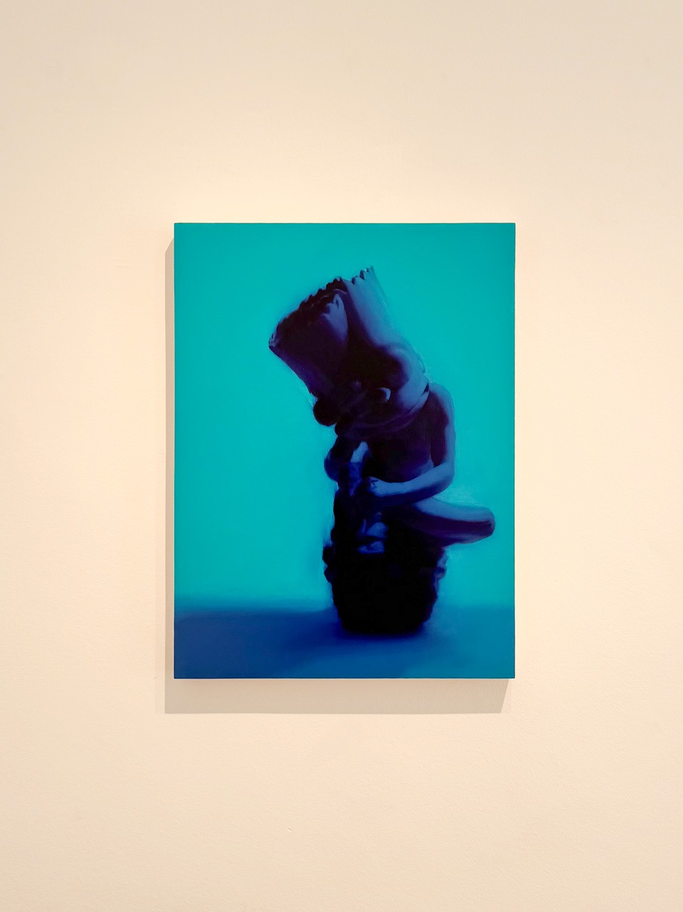 Fever dream (Spinario) II by Nelson Hernández, oil on wooden panel, 24 × 18 cm, on a white wall at Pipeline Gallery. A dark bent figure against an intense turquoise ground.