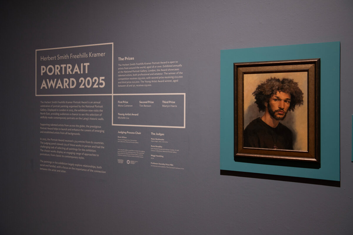 all text panel for the Herbert Smith Freehills Kramer Portrait Award 2025 at the Laing Art Gallery, beside a framed portrait mounted on a teal panel