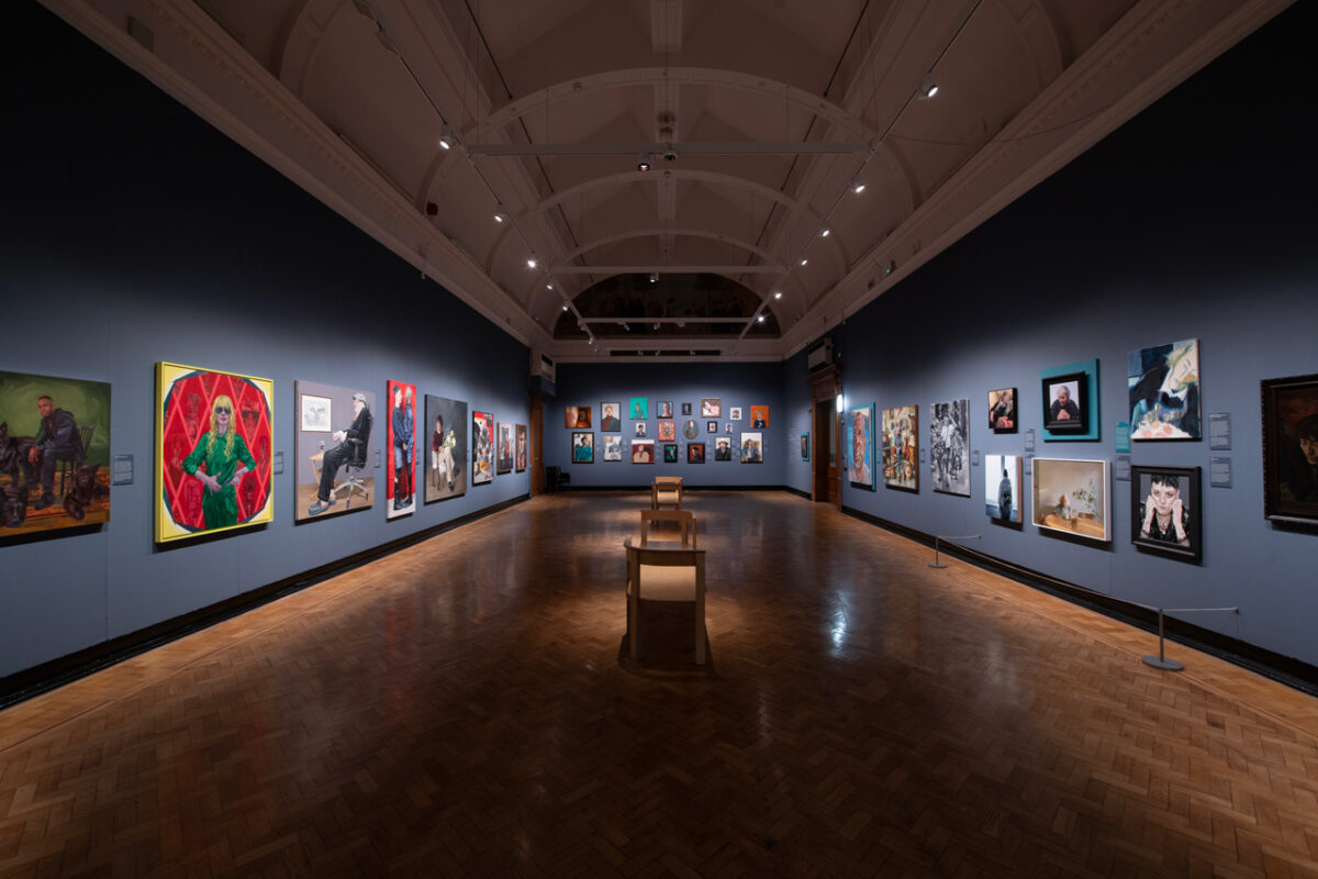 General view of the main gallery at the Laing Art Gallery, portraits hung along both walls beneath a vaulted ceiling, with parquet floor and wooden benches